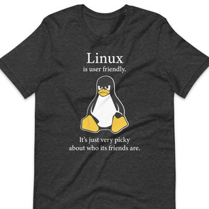 May include A dark gray t shirt with a white pengu
